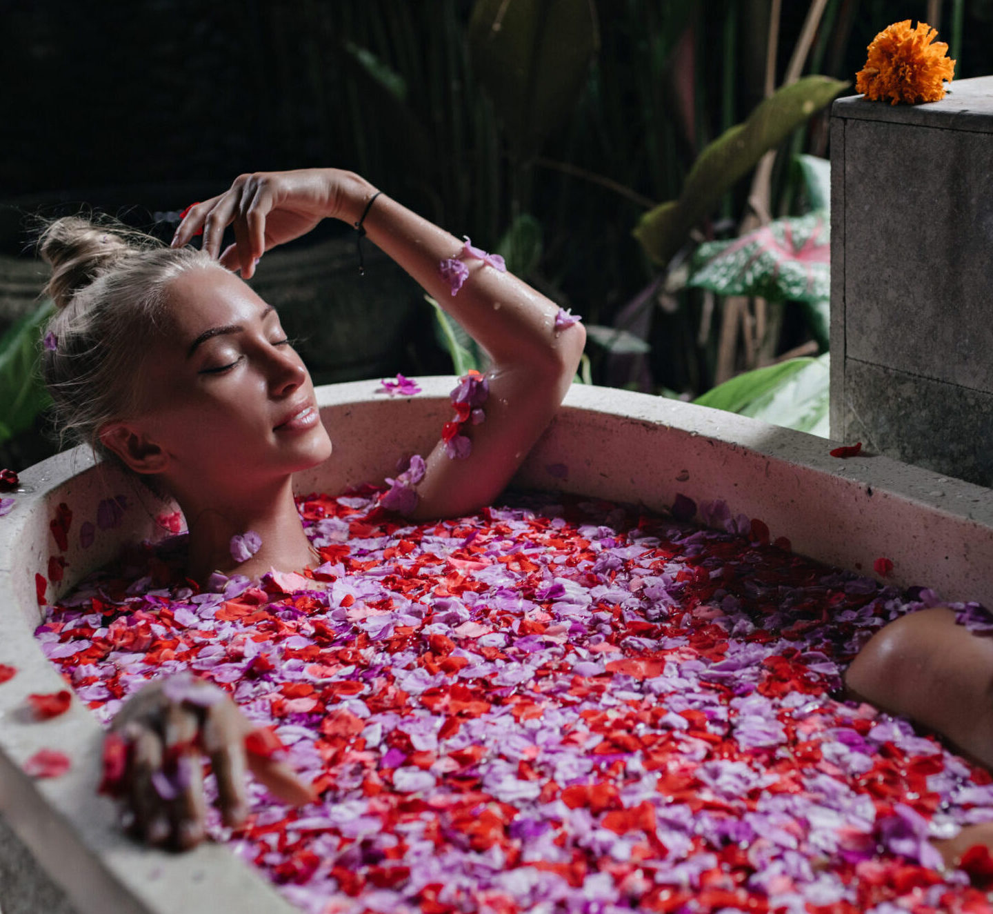 Pleasant woman with tanned skin lying in bath with eyes closed.
